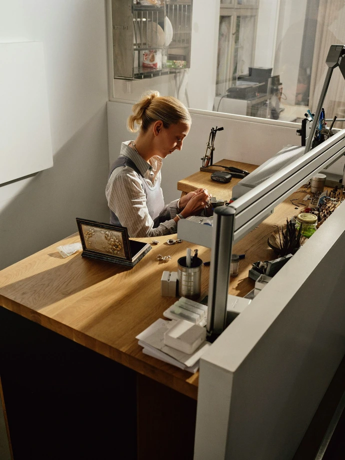 Woman working at a jewelry making bench.